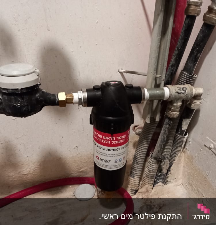 מד מים ומסנן מחוברים לצינורות על קיר